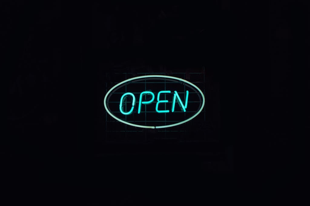 A vibrant neon 'Open' sign glows against a dark backdrop, ideal for business promotions.